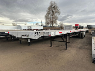 Flatbed trailer showing long low deck with landing legs down, stock number 578 and rear wheels visible.