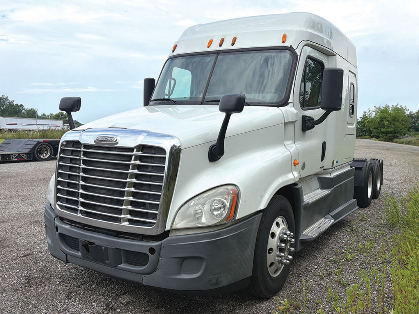 Truck cab exterior of a 2014 Freightliner Cascadia125 Conventional Sleeper showing front grille, headlights, and side mirrors.
