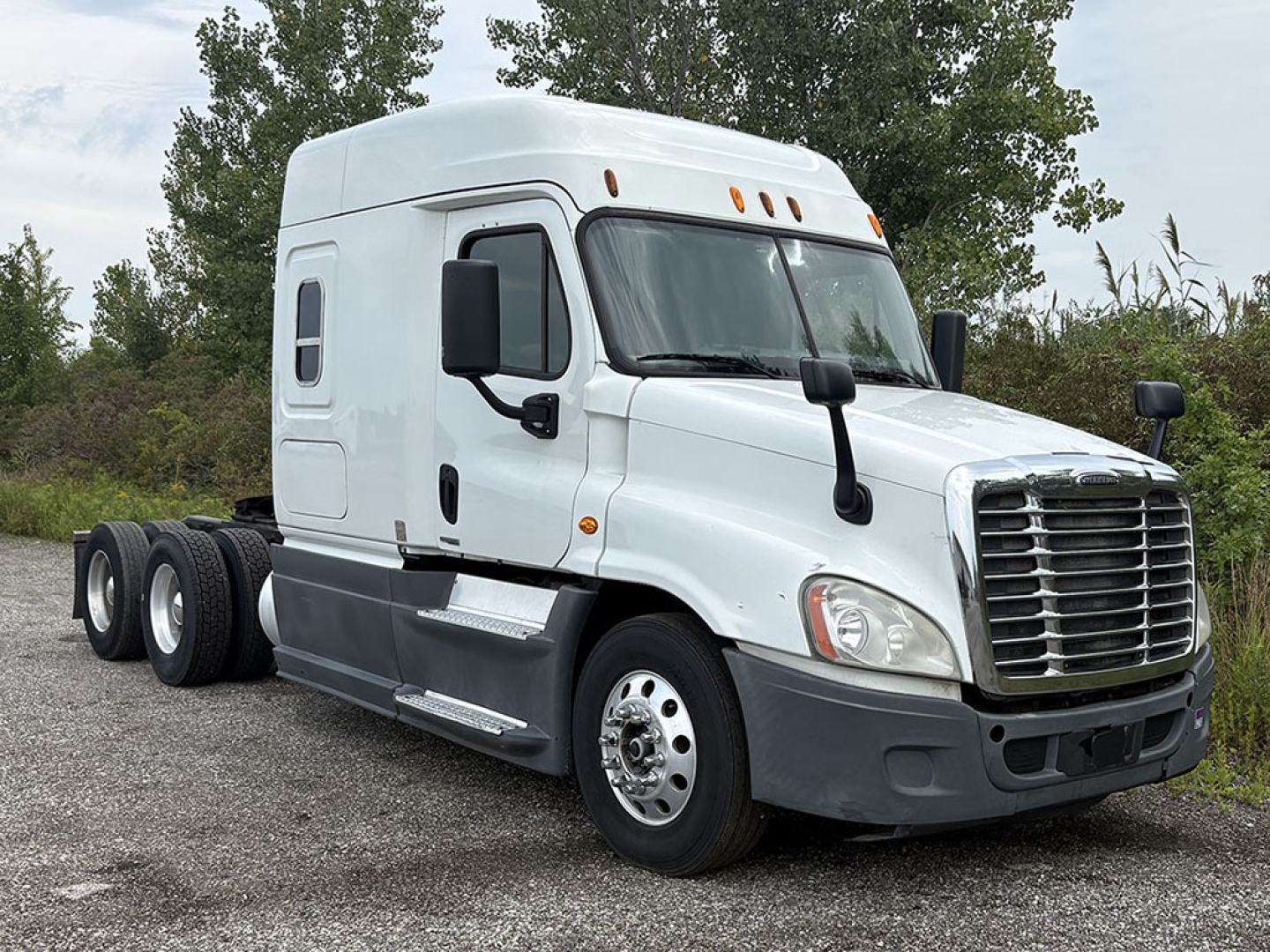 White Freightliner Cascadia125 semi truck with sleeper cab, front grille, side mirrors, black bumper. No visible text labels on the truck.