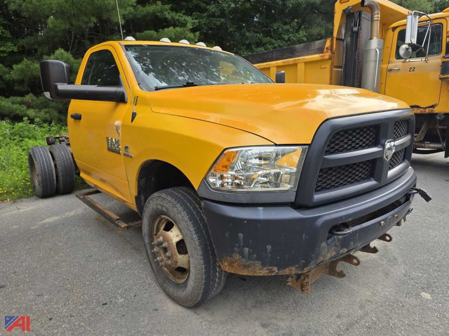 Ram 3500 cab and chassis front-left view showing yellow paint, black grille, Toyota? actually Ram logo; heavy-duty truck with front bumper and wheel wells; visible RAM badge on fender; damaged front bumper and rust on wheel rims.