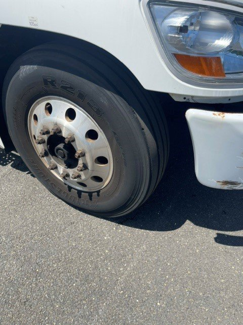 Truck front wheel and fender of a 2014 Hino reefer truck showing tire, wheel, and headlight area.