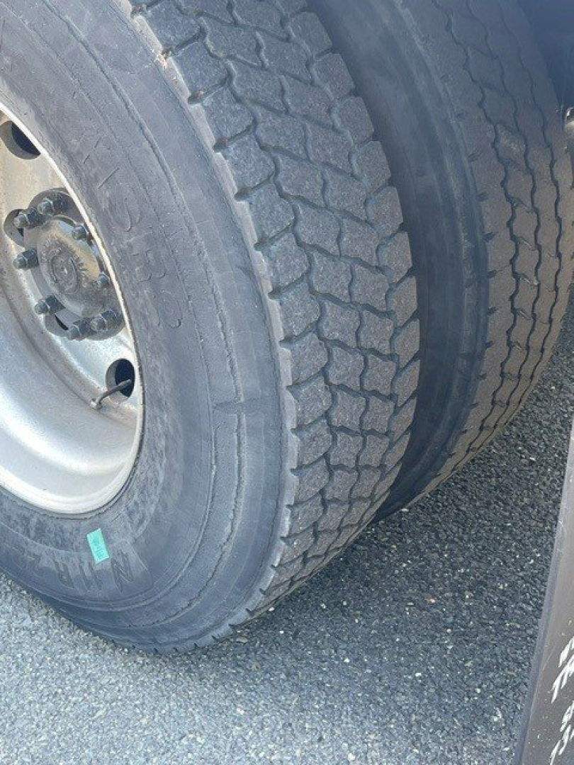 Two rear truck tires with dual wheels and visible lug nuts; part of a reefer truck chassis wheel well.
