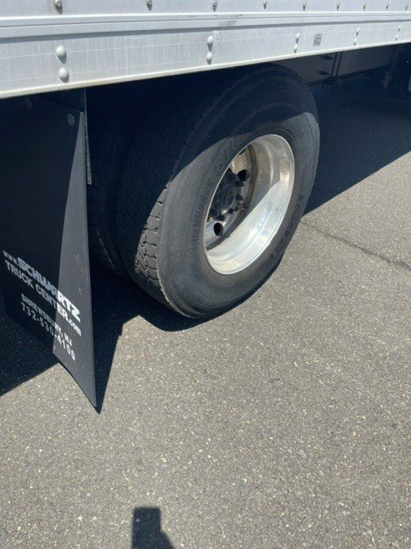 Rear wheel and side panel of a used 2014 Hino 258/268 reefer truck showing dual rear wheels and aluminum cargo body with mudflap.