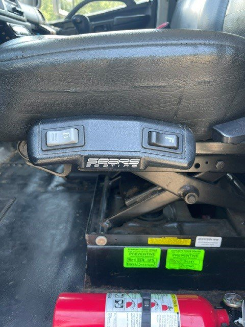 Seat adjustment controls on a Hino reefer truck seat with label nearby and a red fire extinguisher in front.
