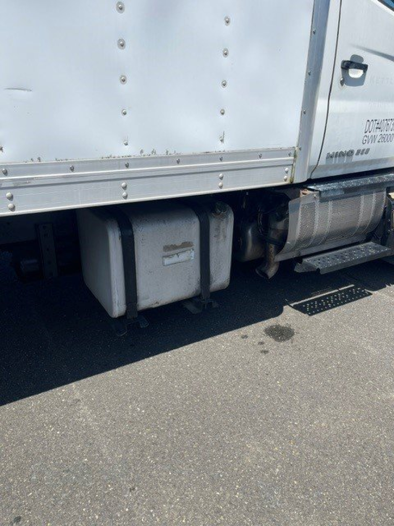 Hino truck side view showing fuel tanks and underbody components with riveted cargo box and steps.