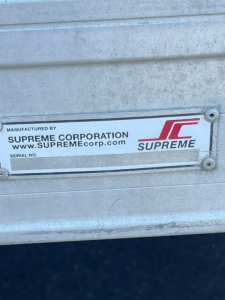 Truck rear door with Supreme Corporation serial plate showing SUPREME logo and website on a metal surface.