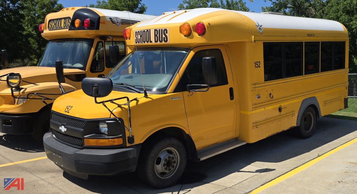 Chevrolet school bus in yellow with 'SCHOOL BUS' sign on roof, front grade bus head, passenger windows, MB2 mini bus model, two yellow buses in background.