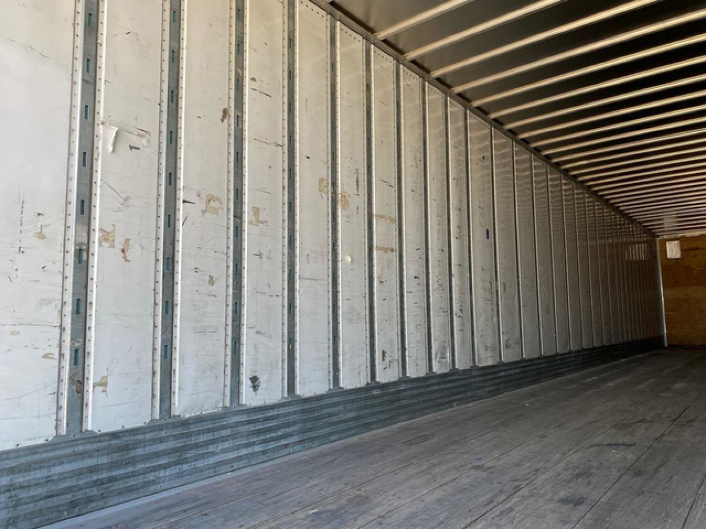 Trailer interior showing empty cargo area with metal side walls and wooden floor panels.