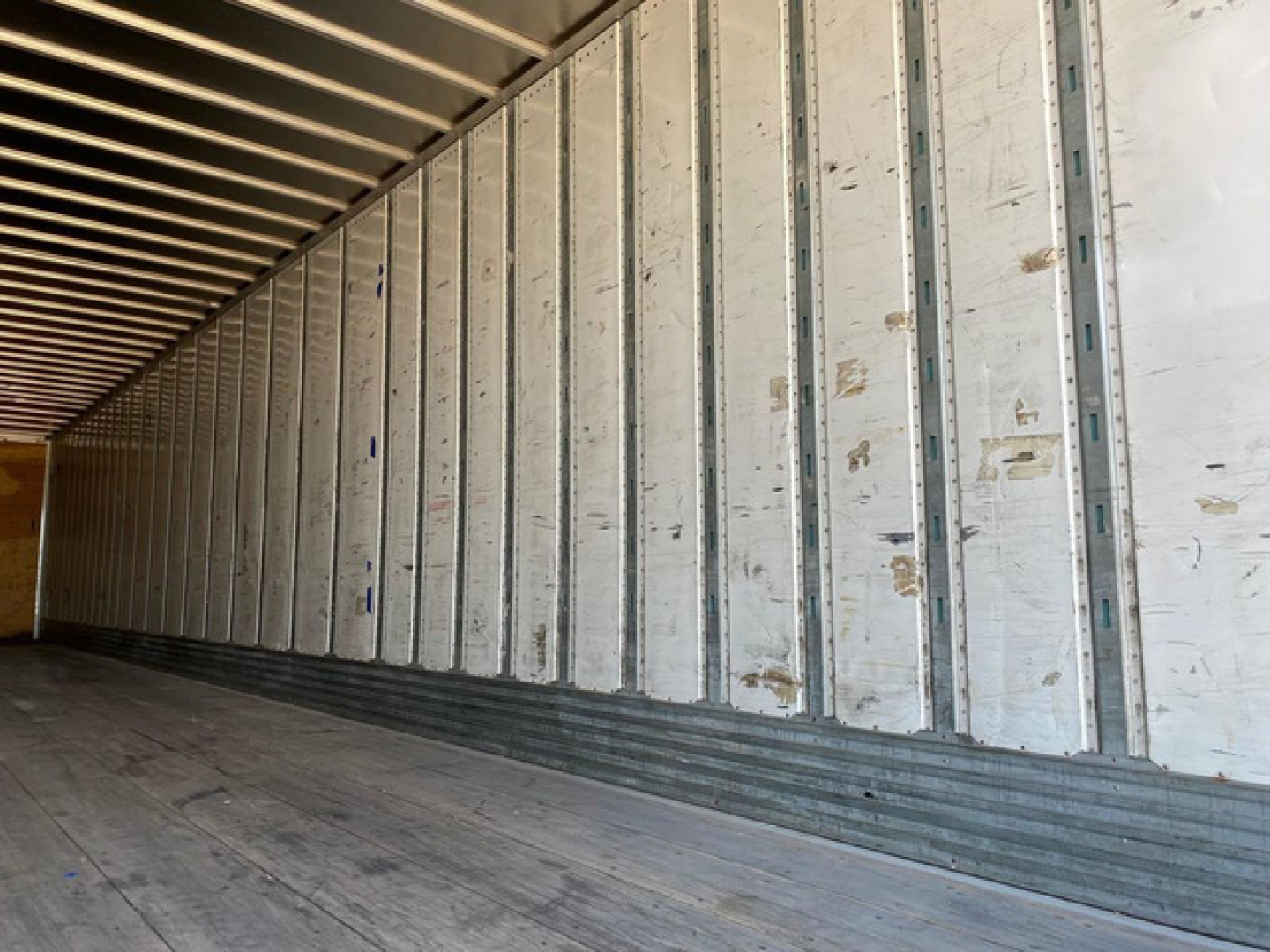 Van trailer interior with metal side walls and wooden floor, shown in a long loading area.