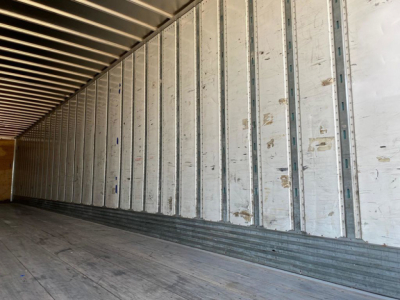 Van trailer interior with metal side walls and wooden floor, shown in a long loading area.