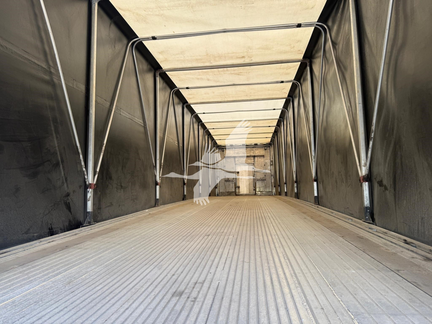 Trailer interior showing empty curtainside trailer with ribbed aluminum floor and metal support beams.