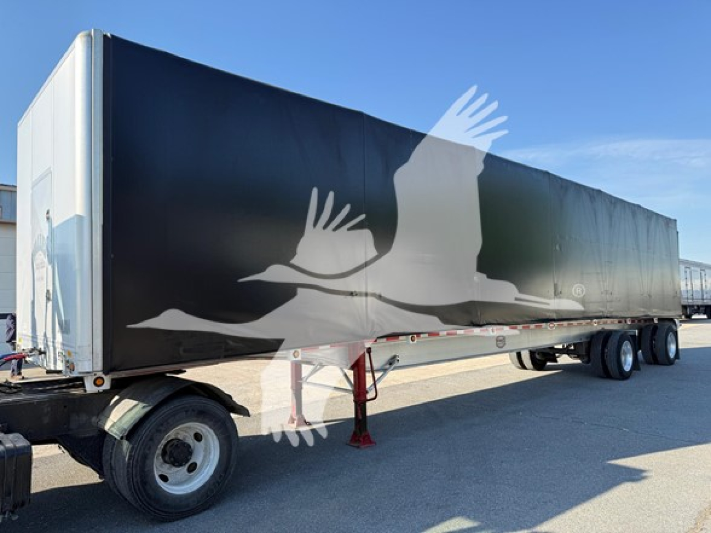 Trailer side showing large graphic of a flying bird or eagle on black background; front wheel and support legs visible; no detailed text legible.