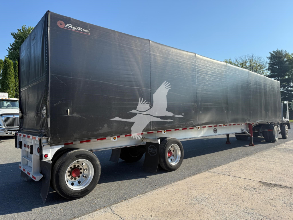 Curtainside trailer showing large black vinyl cover with white bird graphic, rear and side view, with wheel axles and undercarriage visible.
