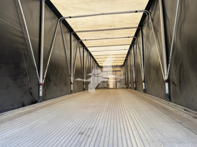 Trailer interior showing empty curtainside trailer with ribbed aluminum floor and metal support beams.