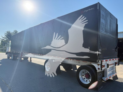 Curtainside trailer in serviceable condition showing a black weather cover with white bird graphic and rear lights; Mac Aluminum Flat 2013 trailer.