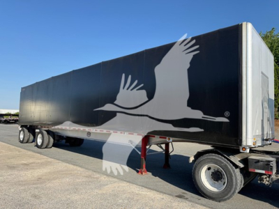 Flatbed trailer showing black curtainside with white bird graphic, side view, undercarriage and wheels visible.