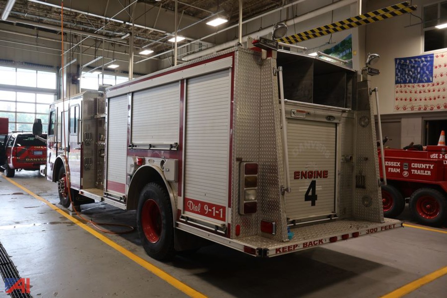 Fire truck cab over engine with rear compartment doors and 'ENGINE 4' lettering inside a workshop
