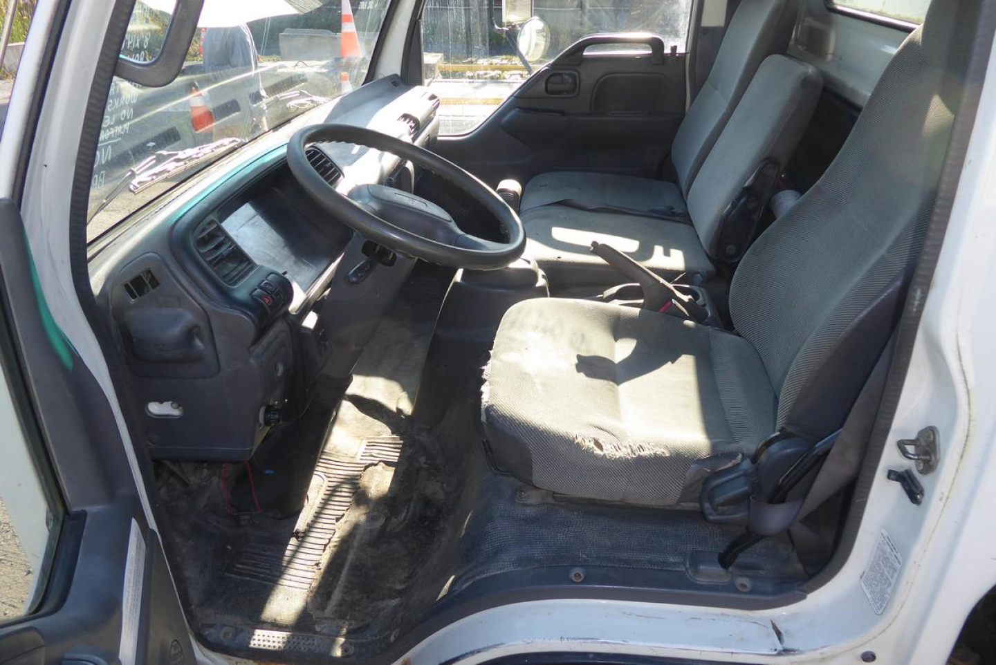 GMC W4500 truck interior showing driver's seat and front bench with steering wheel, dashboard, and passenger seat.