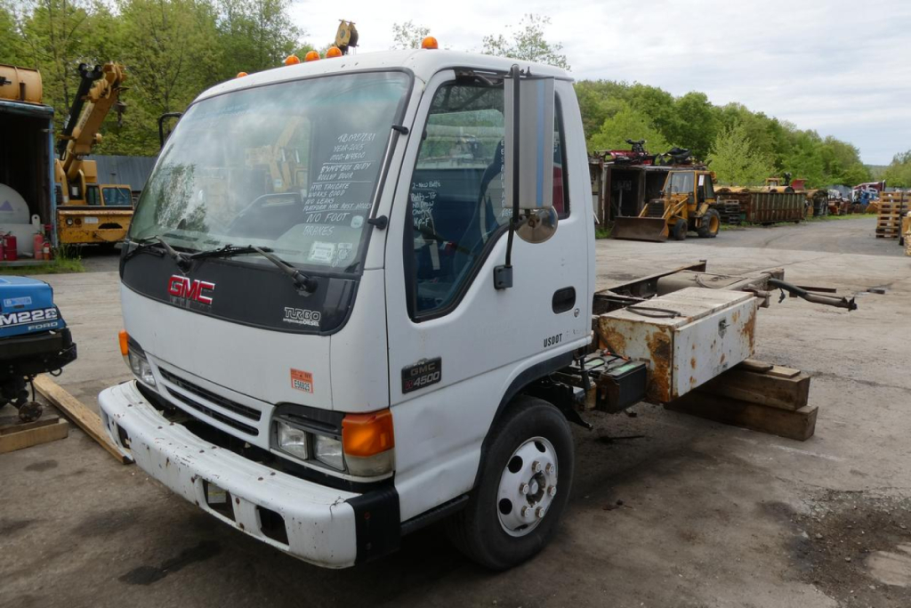 GMC W4500 truck in yard showing cab and chassis with white body and orange marker lights.