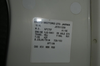 Vehicle label on Isuzu/GM truck showing VIN J8DC4B16657011209, M.D. NPC75F, ENGINE RJS/4HK, TRANS RNJ, FINAL RU1, TIRE AZF, B.COLOR/TRIM 729/153, OPTION C60 K51 NB6 RQG.
