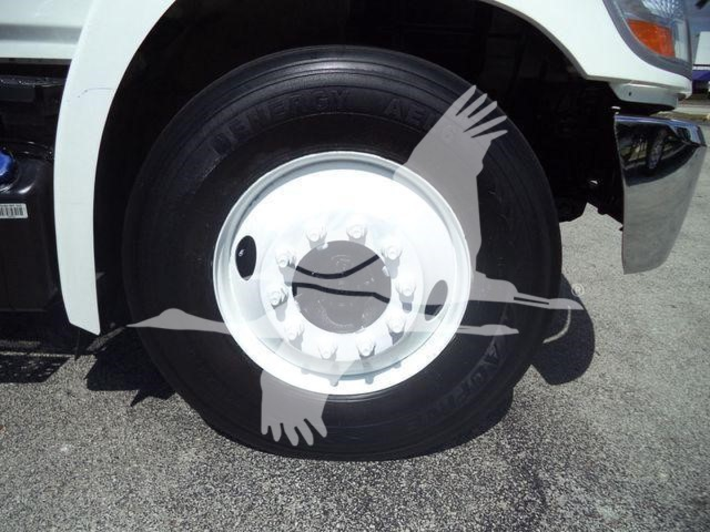 Truck wheel and tire close-up with white rim on 2016 Hino 268A dump truck showing tire tread and wheel cover.