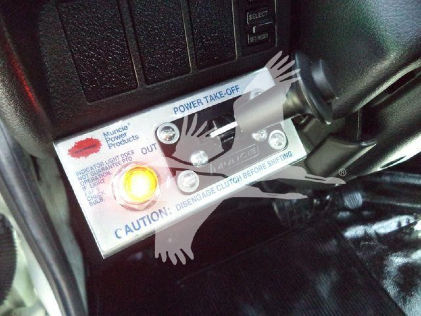 Close-up of a panel showing a Power Take-Off (PTO) lever with labels: 'Power Take-Off', 'Disengage Clutch Before Shifting', 'Caution', with a circular orange indicator light.