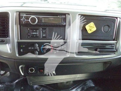 Dashboard of a 2016 Hino 268A cab showing radio/CD unit, climate controls, dashboard switches, and a yellow maintenance sticker on a panel.