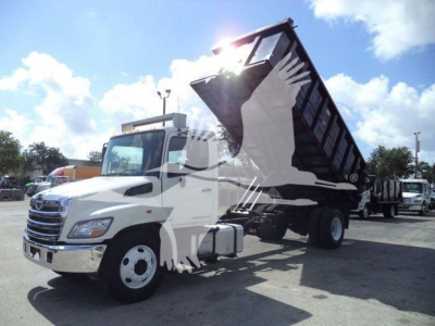 White 2016 Hino 268A dump truck with a raised black steel dump bed in a parking lot.