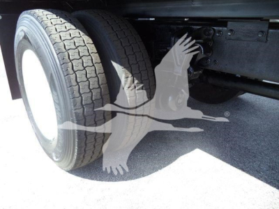 Wheel and dual rear tires of a dump truck showing tire tread and undercarriage components.