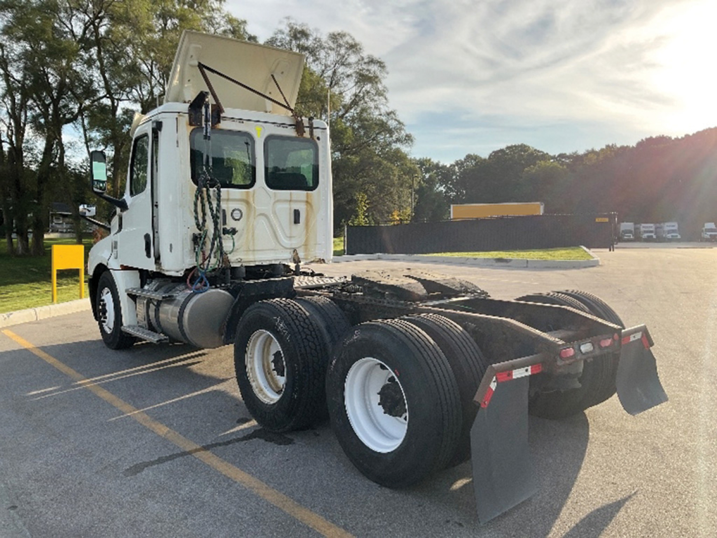 Truck rear view of a Freightliner Cascadia126 tractor with fifth wheel and dual rear axles in a parking lot.
