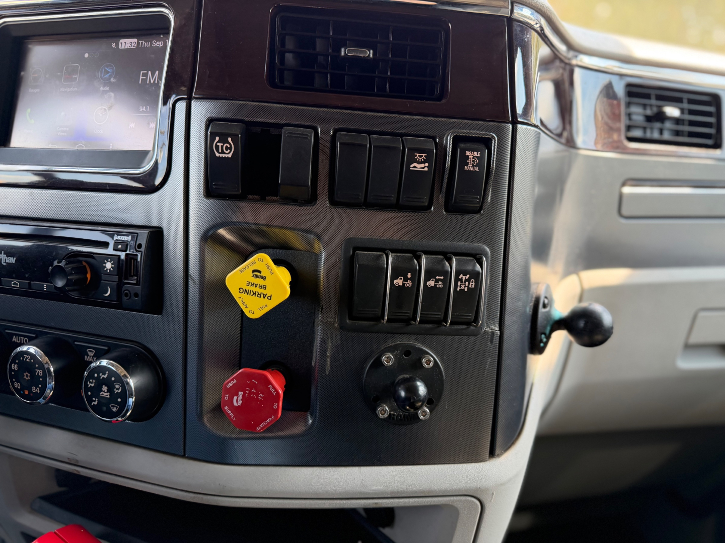 Peterbilt 579 truck interior dash with control switches and knobs; yellow and red knobs visible.