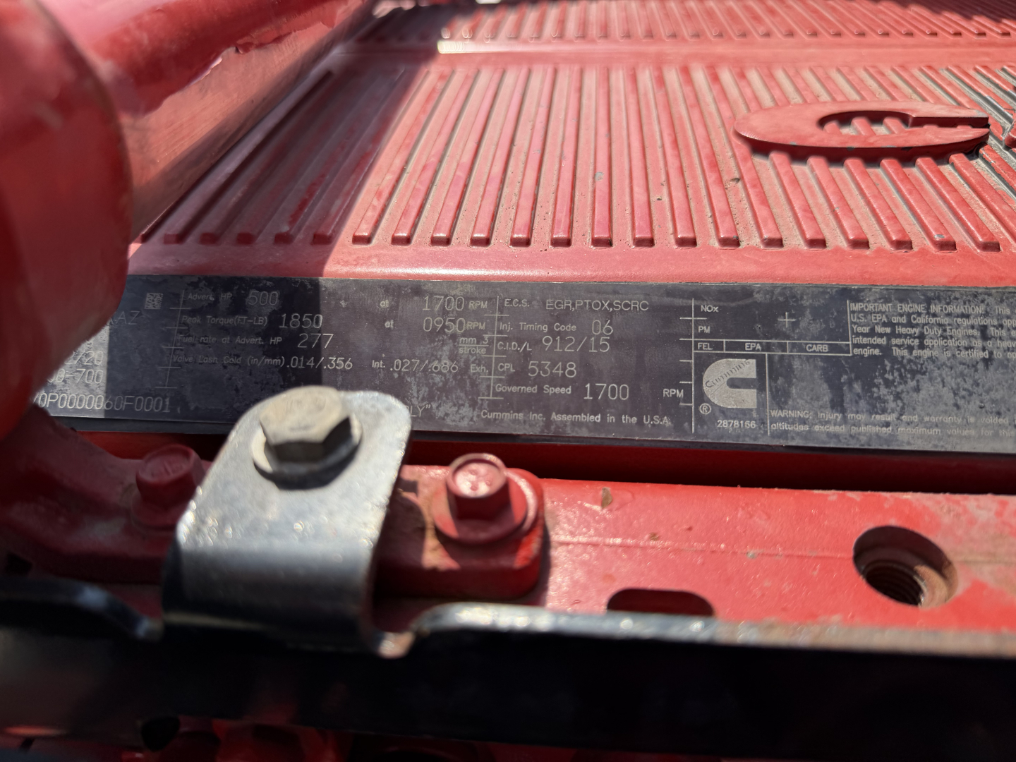 Peterbilt 579 engine bay area showing data label with specs and VIN plate; visible numbers include 1700 RPM, weight/axle details, plus various small text on the black plate.