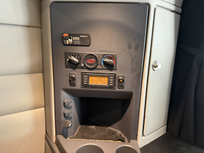 Peterbilt 579 sleeper cab dash area with control panel, gauges, and a digital display. Visible text includes safety labels and switches on the center console.