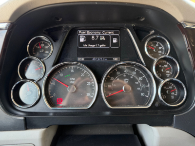 Peterbilt 579 instrument cluster showing fuel economy screen and multiple gauges including RPM, speedometer, and engine temperature.
