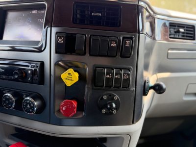 Peterbilt 579 truck interior dash with control switches and knobs; yellow and red knobs visible.