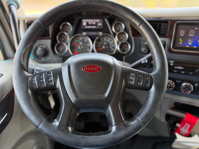 Peterbilt steering wheel and dashboard view in a Peterbilt 579, with circular gauges behind steering wheel and a touchscreen display to the right.