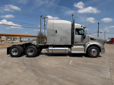 Peterbilt 579 truck side view showing sleeper cab, chrome fuel tanks, six-wheel rear axle, and bare chassis.