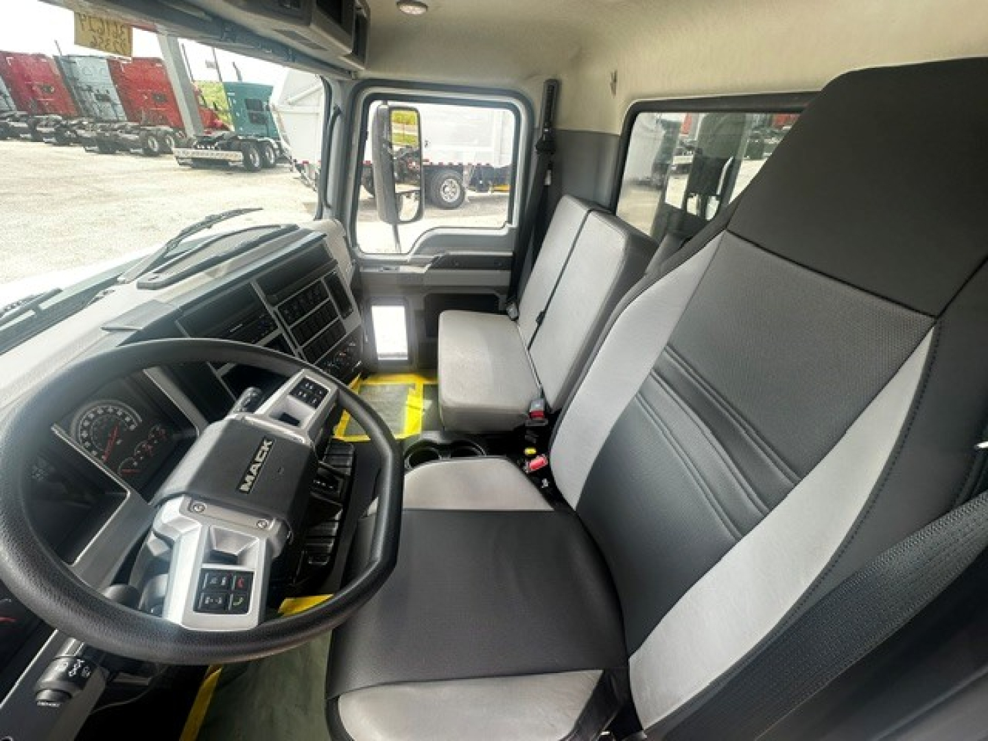 Cab interior of a new 2027 Mack MD7 dump truck showing steering wheel, dashboard, and front seats.