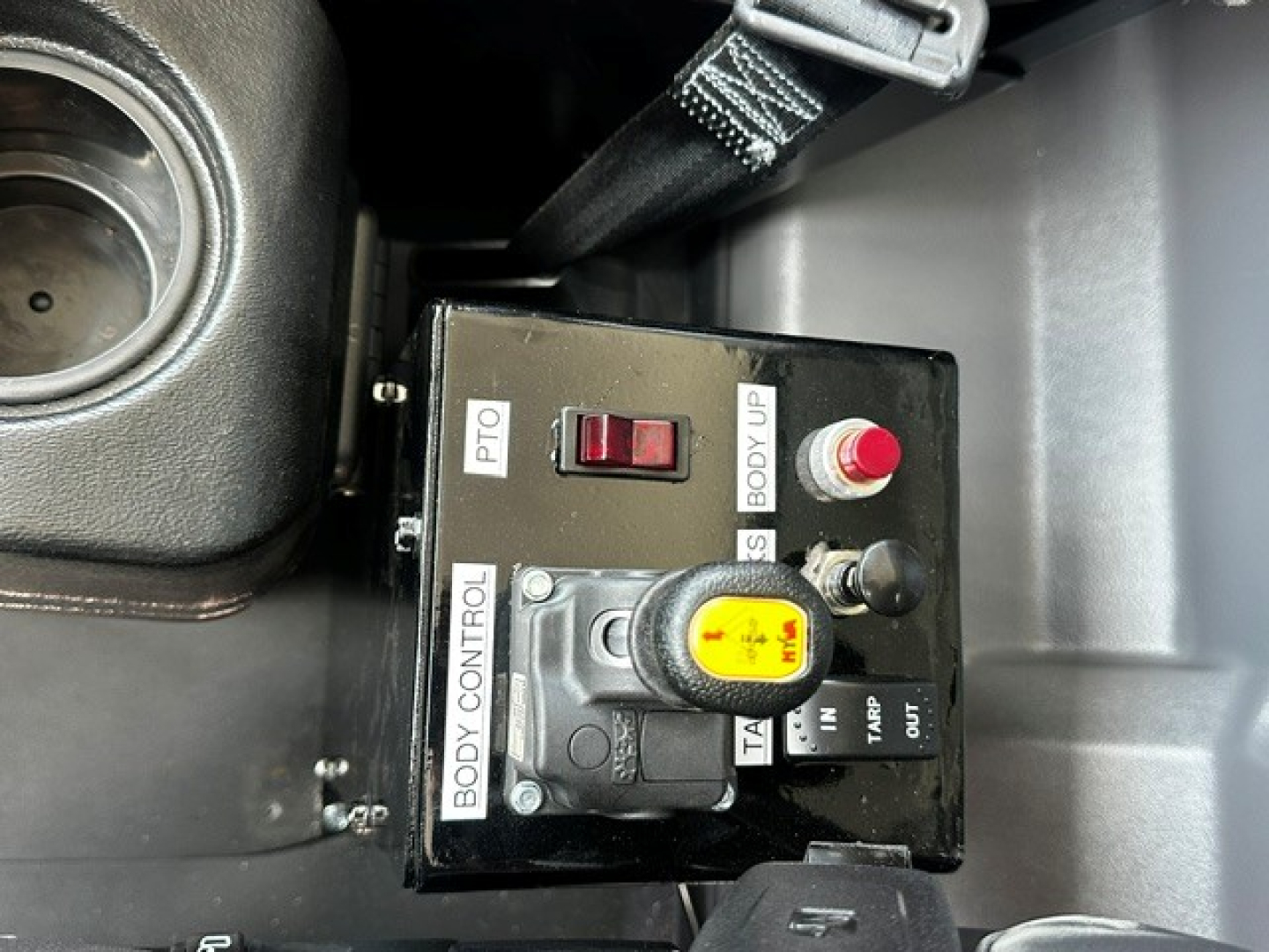 Dash-mounted control box with yellow knob and red button labeled BODY CONTROL, PTO, BOOT UP, and TA; part of Mack MD7 truck interior view