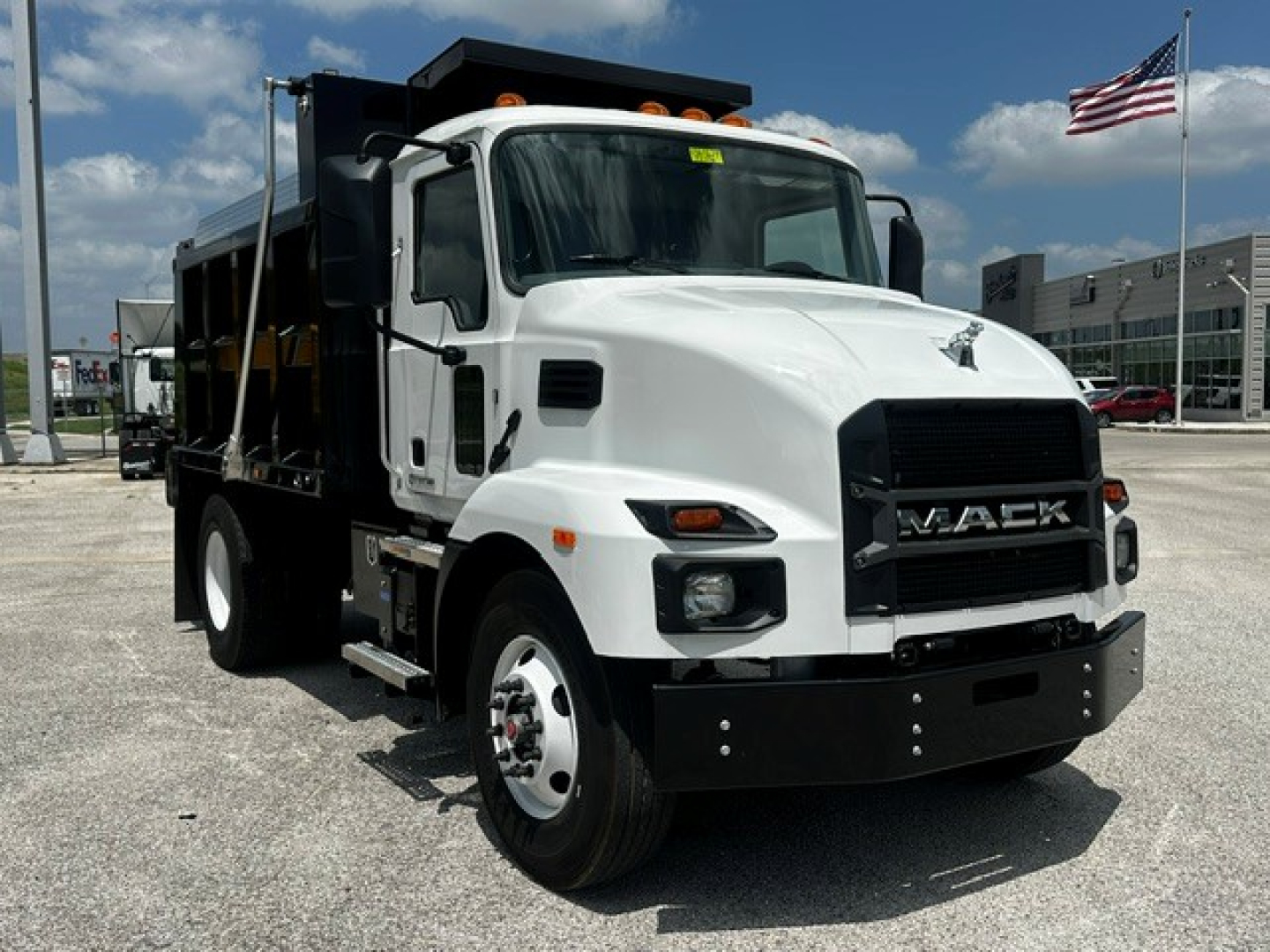 Mack MD7 dump truck in white, front three-quarter view with black grille and load bed visible.