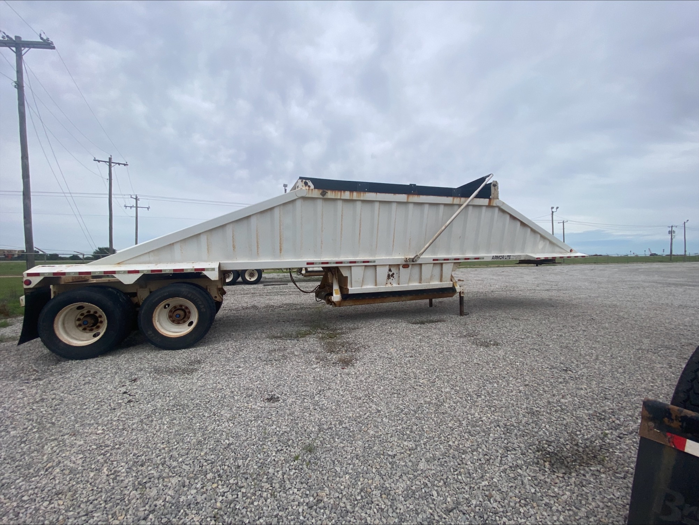 Dump trailer in-service showing Armor Lite SBD40 skeleton dump trailer with dual rear axles and empty cargo bed.