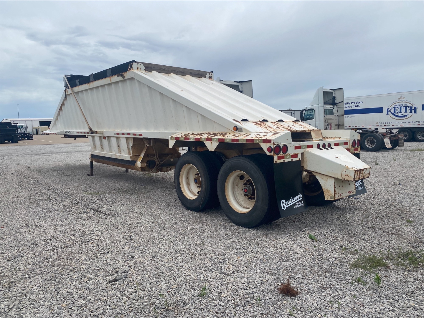 Dump trailer showing Armor Lite SBD40 skeleton bed with dual rear axles and white-painted steel frame.
