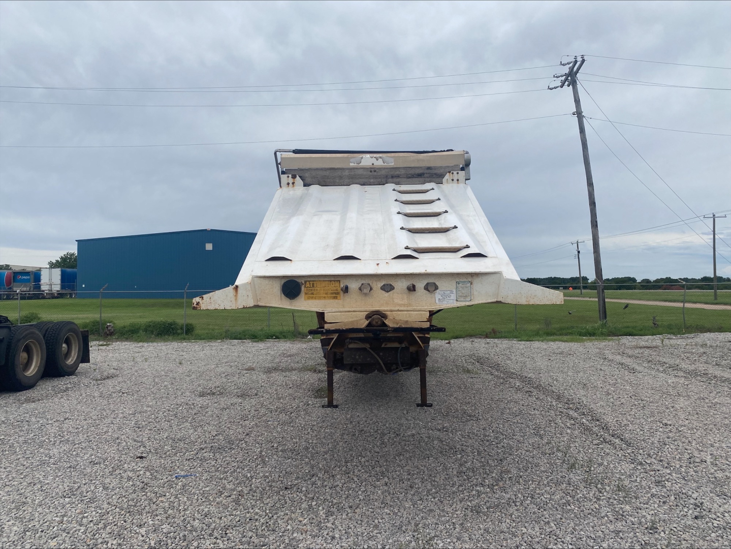 Dump trailer rear view showing Armor Lite SBD40 skeleton dump bed with hydraulic mechanism and support legs.
