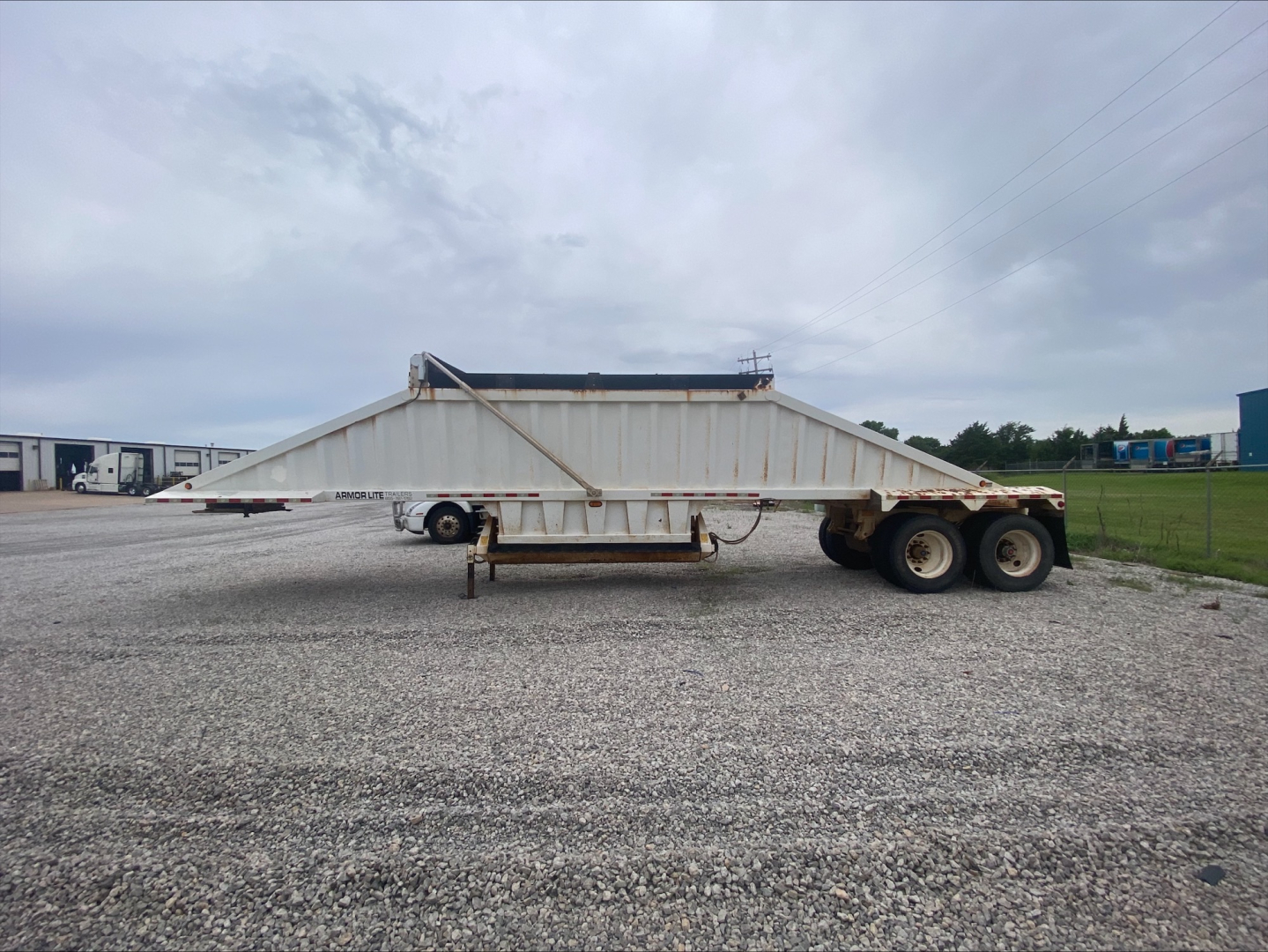 Dump trailer sideways view showing Armor Lite SBD40 spring skeleton with dual rear axles and elevated side walls.