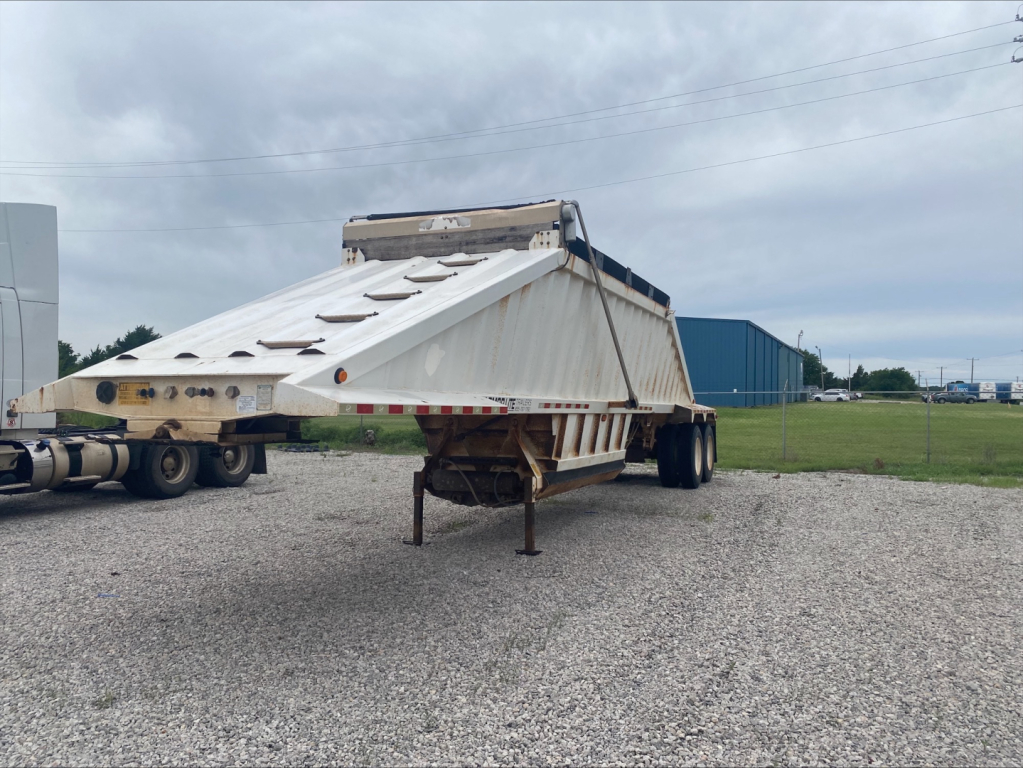 Dump trailer in stand, rear view showing Armor Lite SBD40 skeleton dump trailer with hoist and landing gear.