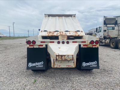 Dump trailer rear view showing Armor Lite SBD40 with rusted bed edges, taillights, mud flaps labeled Bruckner’s Equipment, gravel surface.