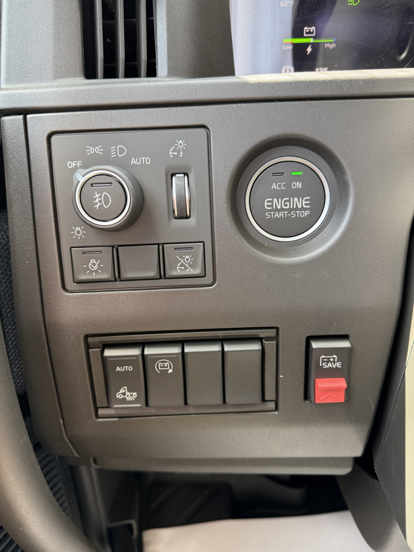 Dashboard controls visible: headlight switch with auto; engine start-stop button labeled ENGINE START-STOP; several rocker switches; indicator icons and a red 