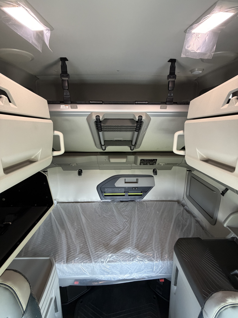 Volvo VNL64T860 sleeper cab interior showing overhead storage and bunk area with plastic-covered mattress.