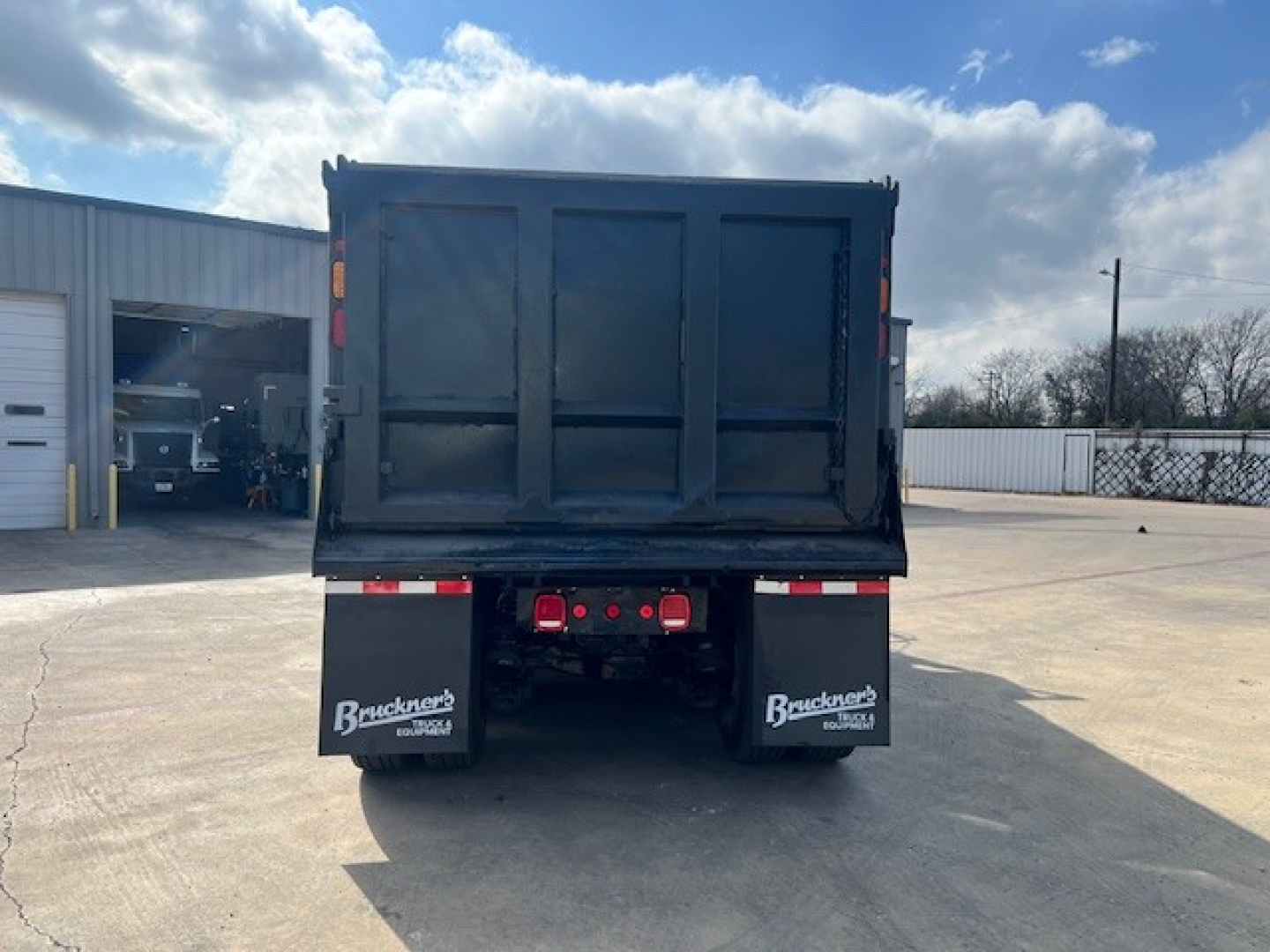 Dump truck bed of a 2018 Mack GU713 viewed from rear, showing the open-top cargo bed and rear bumper with taillights. Stock and VIN not visible.