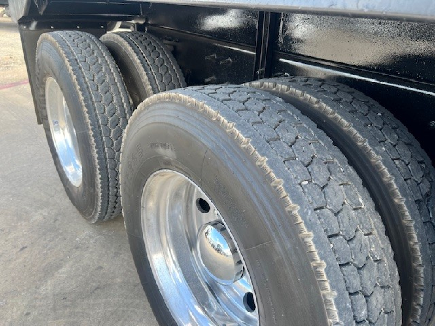 Truck rear dual wheels with heavy-duty tires and polished chrome rims on a Mack GU713 dump truck chassis.
